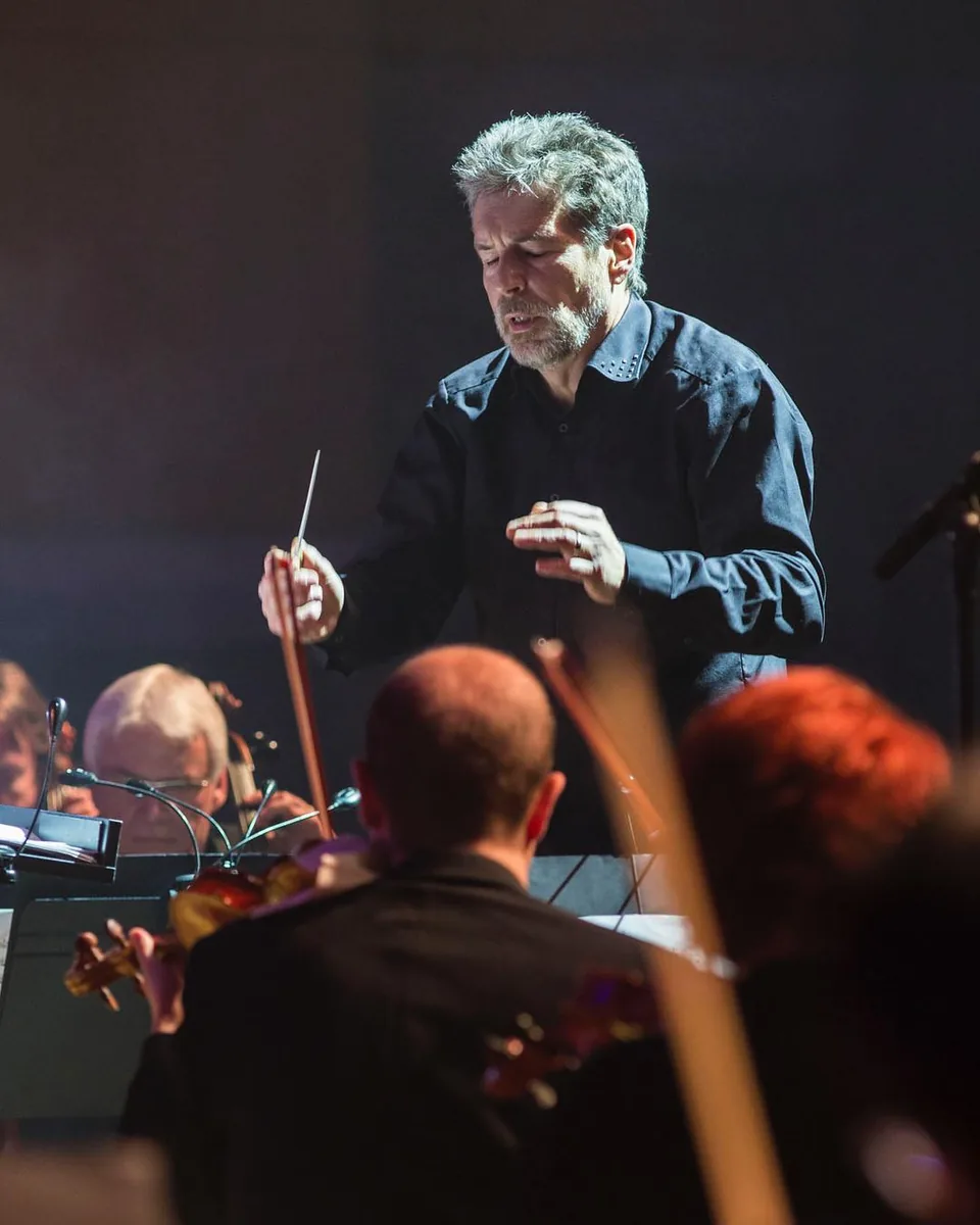 Conductor leading an orchestra during a live concert by Andreas Düren