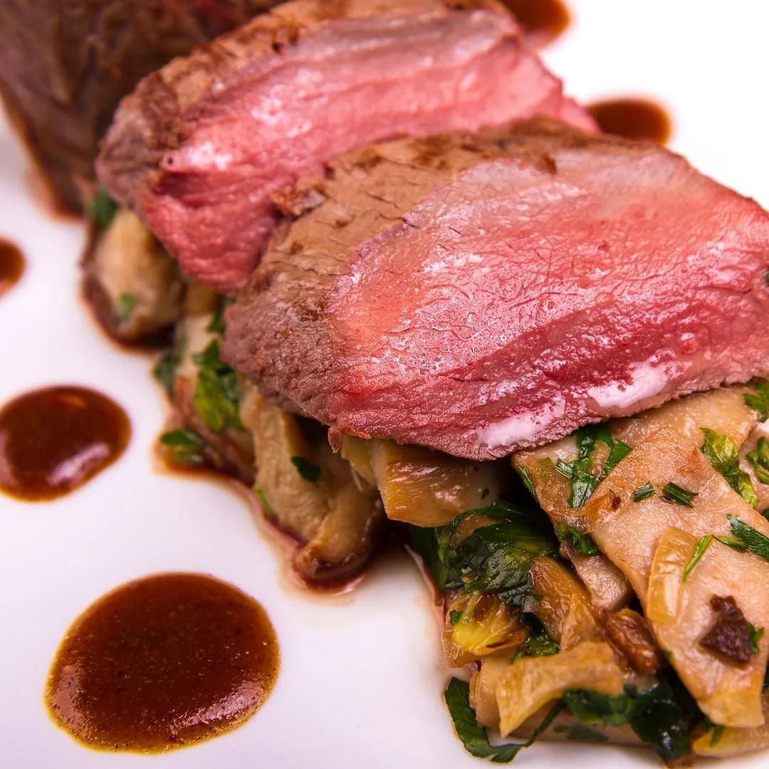 Close view of plated venison with mushrooms and sauce by Andreas Düren