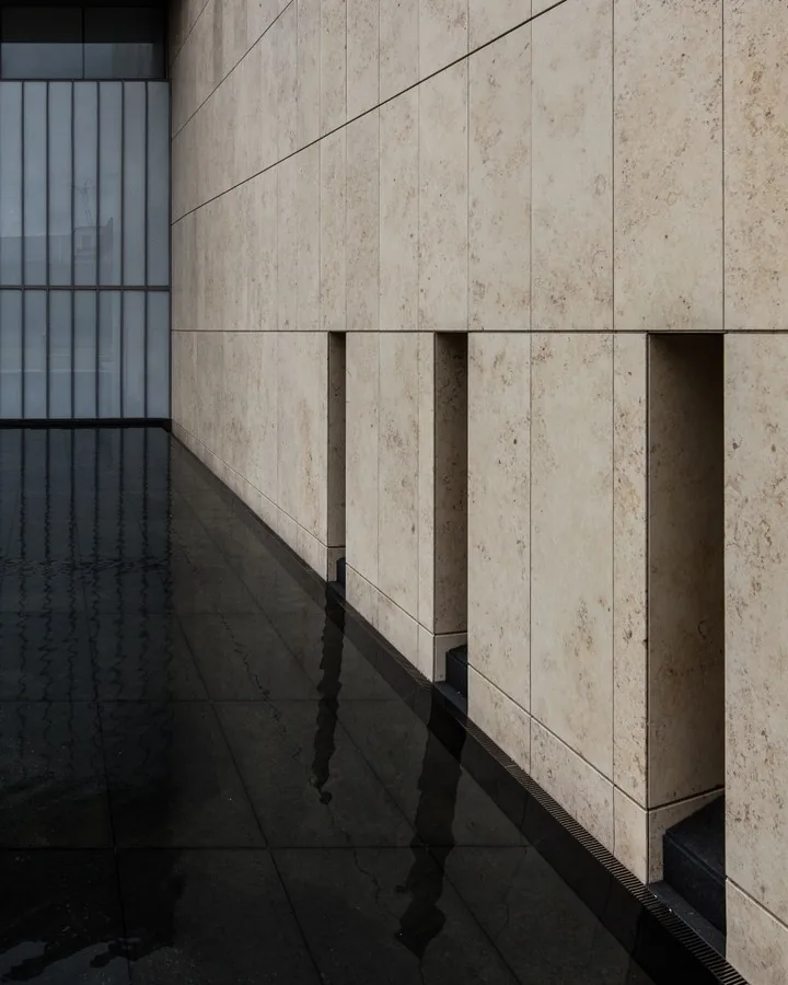 Geometric stone façade reflected in dark water in Tokyo by Andreas Düren