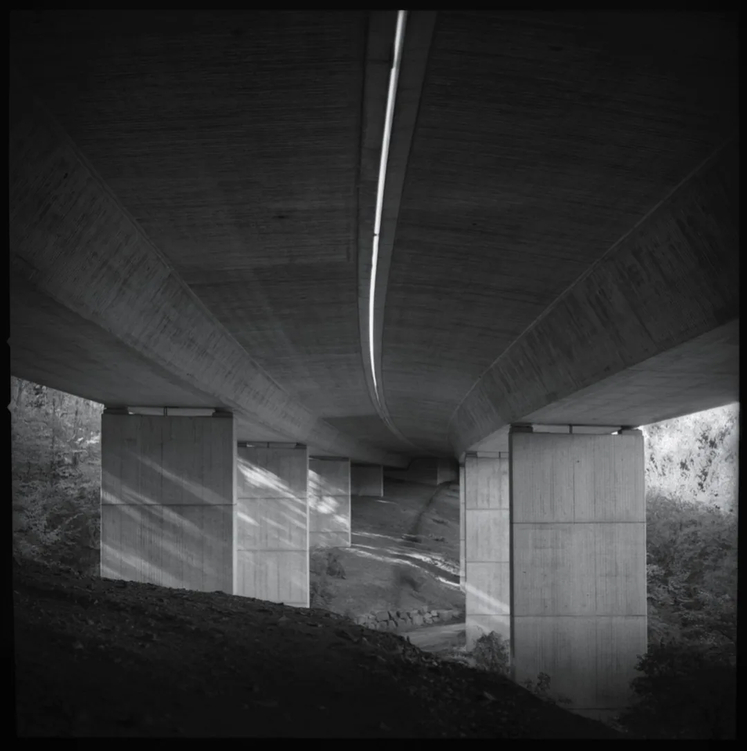 Black-and-white view beneath a concrete motorway bridge by Andreas Düren